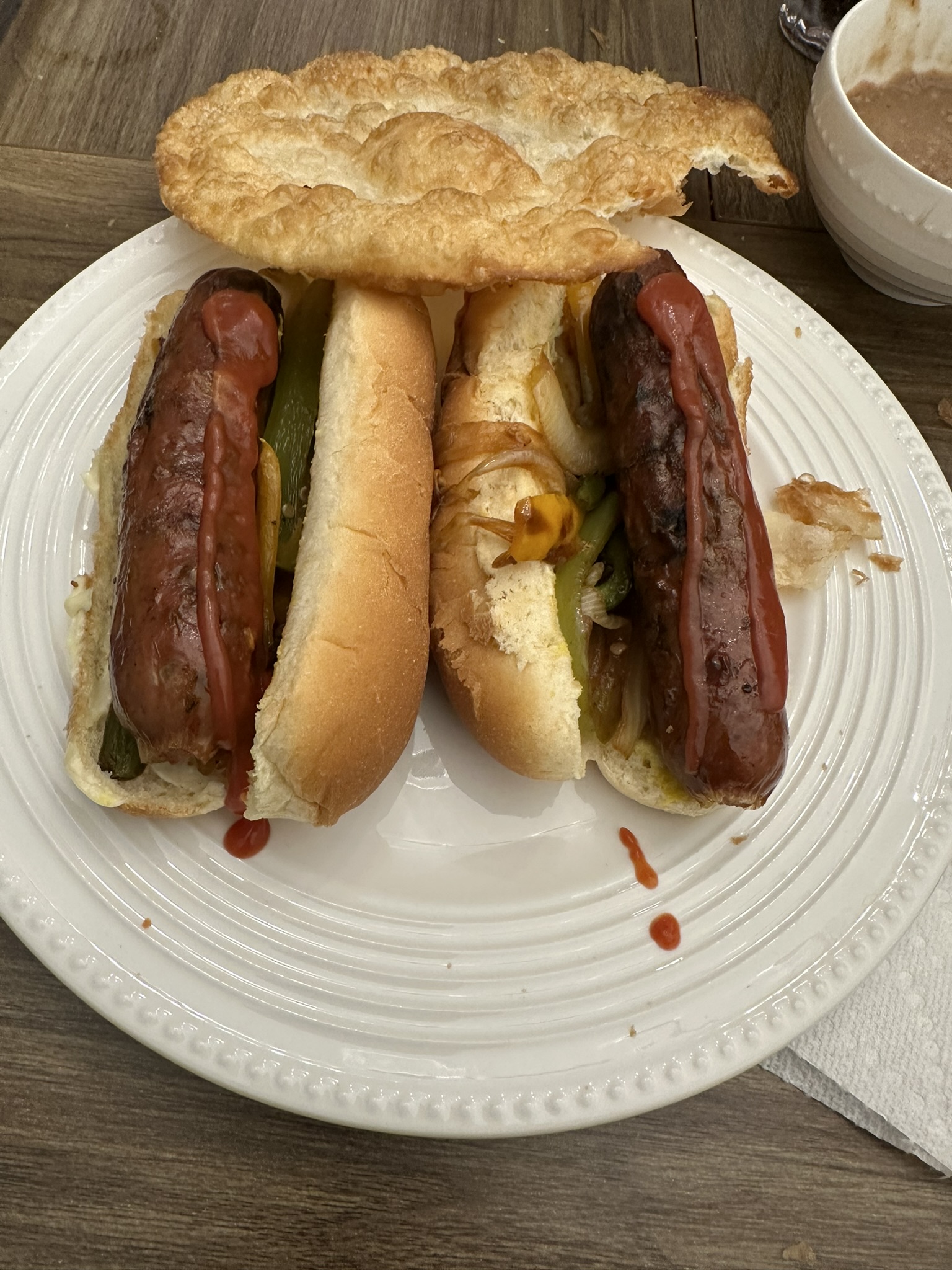 Two grilled sausage dogs with peppers and onions