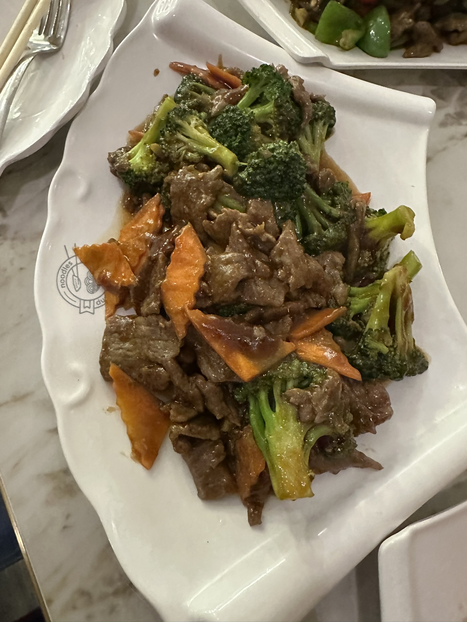 Beef and broccoli stir-fry on a scalloped plate