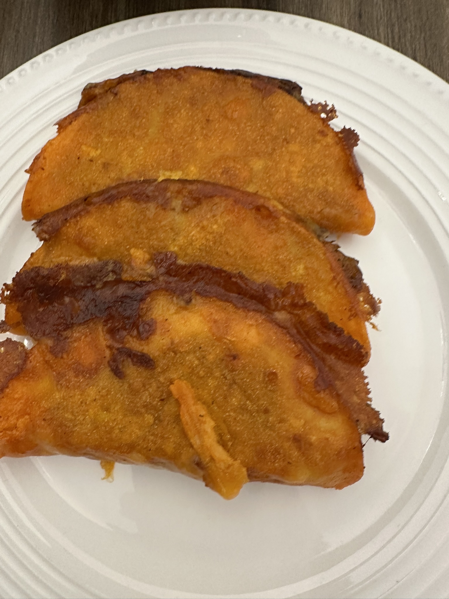 Crispy birria tacos stacked on a white plate